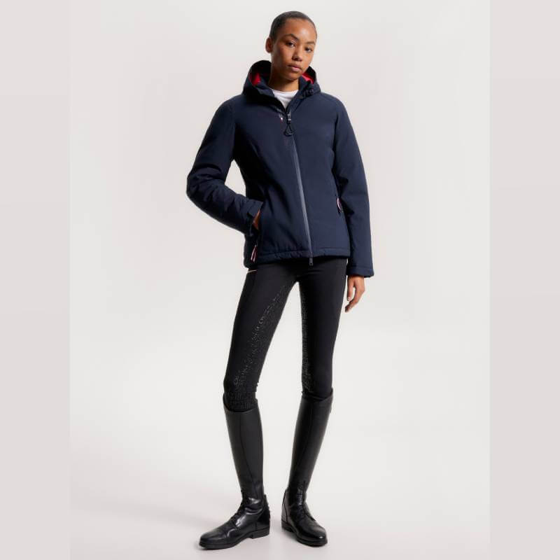 Woman in a Tommy Hilfiger London Winter Riding Jacket Desert Sky, black pants, and riding boots.