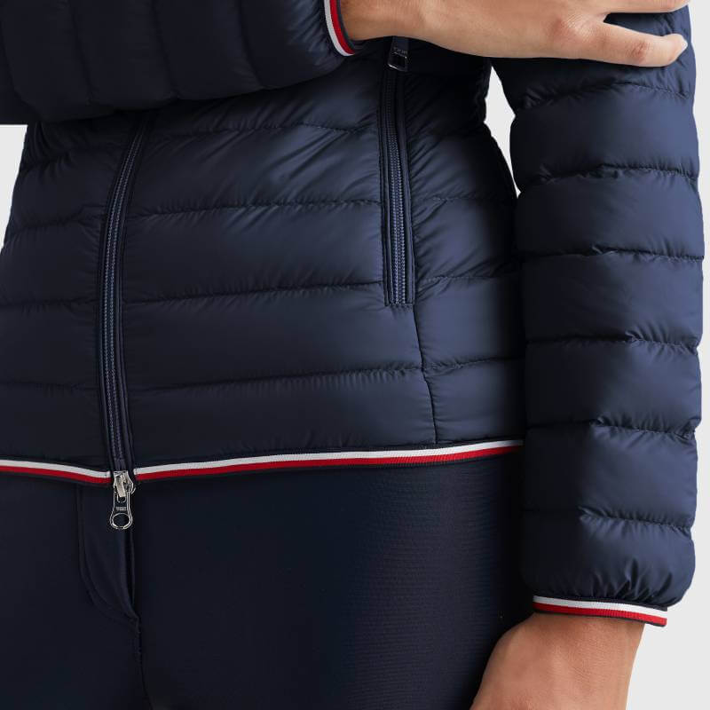 A woman in a Tommy Hilfiger Women Light Re-Down Jacket in Desert Sky.