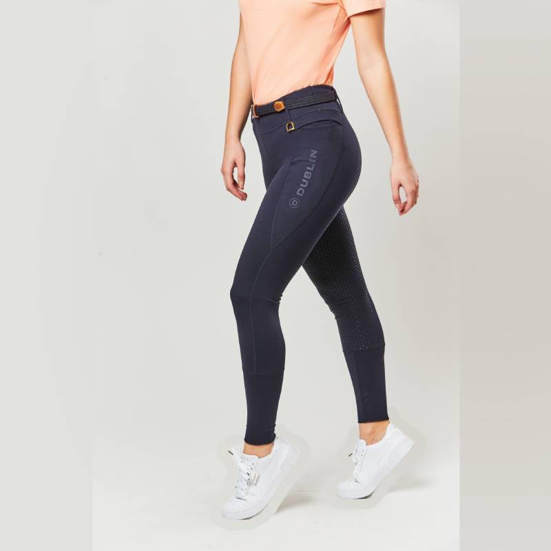 Woman in navy Dublin Cool It Everyday Riding Tights and white sneakers on a plain background.