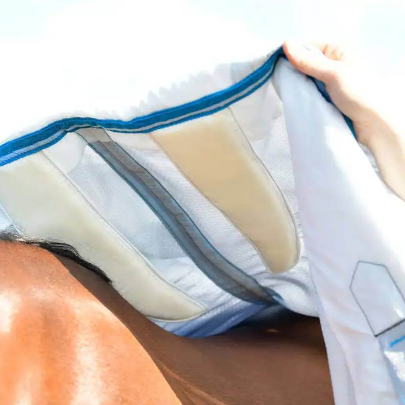 A person puts a Weatherbeeta Comfitec Hexi Shield Silver/Teal Blue rug on a horse in sunlight.