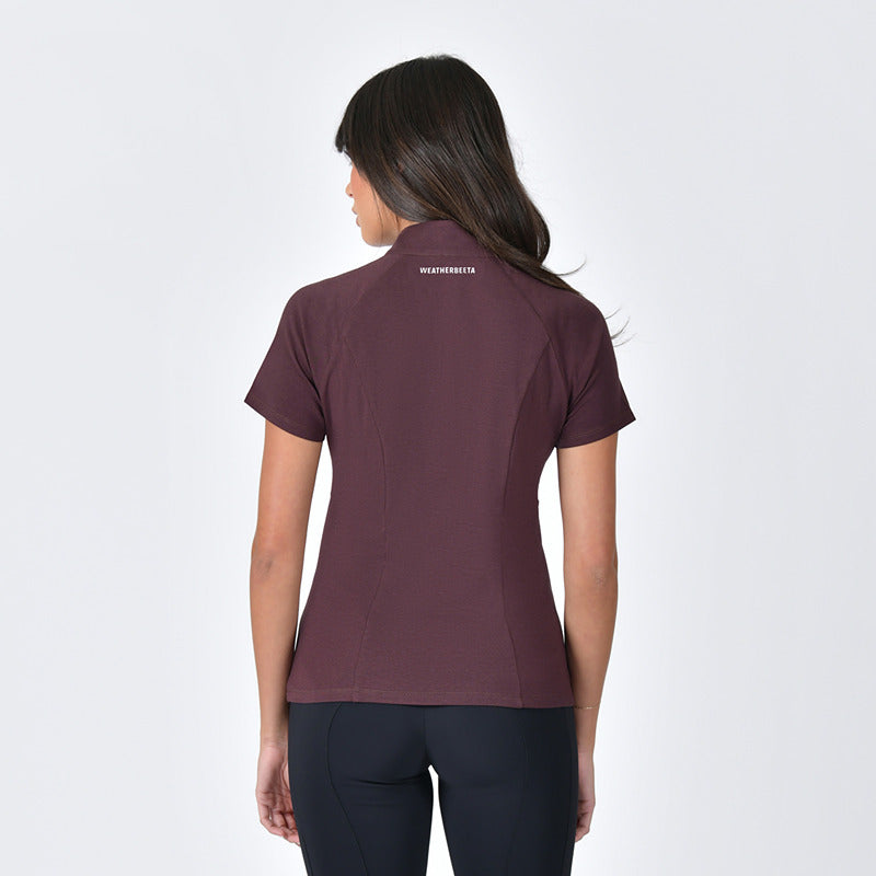 Woman wears a Weatherbeeta Bamboo Short Sleeve Base Layer Mulberry and black pants on a white background.