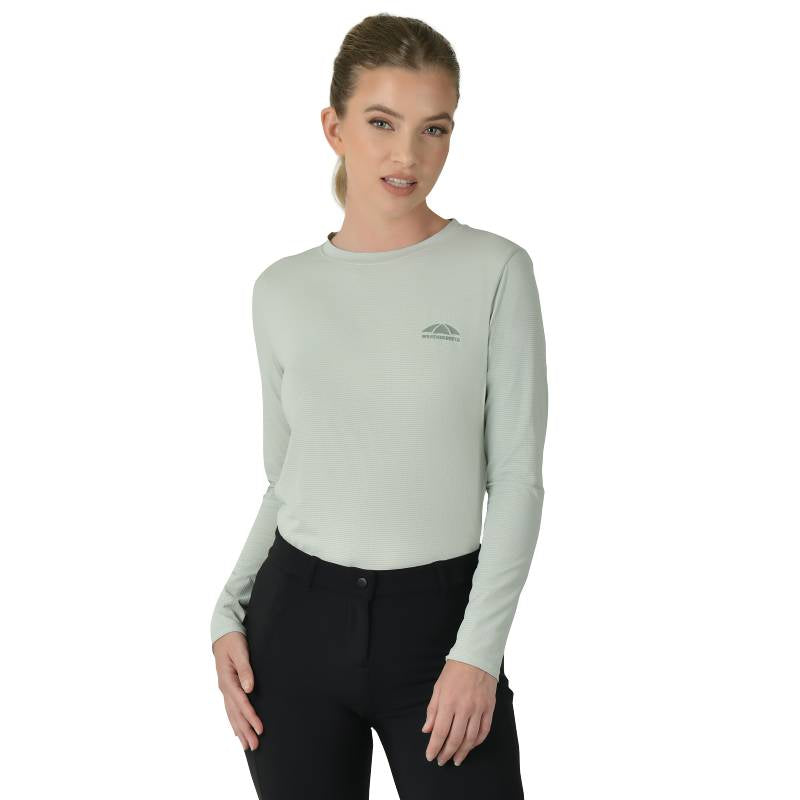 Woman in Weatherbeeta Relaxed UV Long Sleeve Tee Soft Sage and black pants against white background.