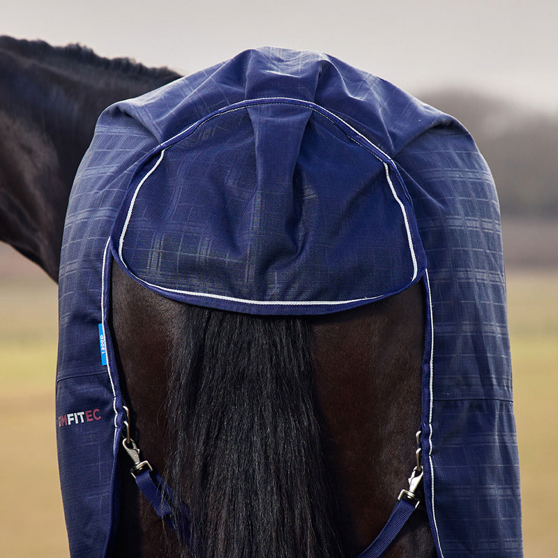 A horse wears a Weatherbeeta Comfitec Prelim Navy Plaid turnout rug in a field.