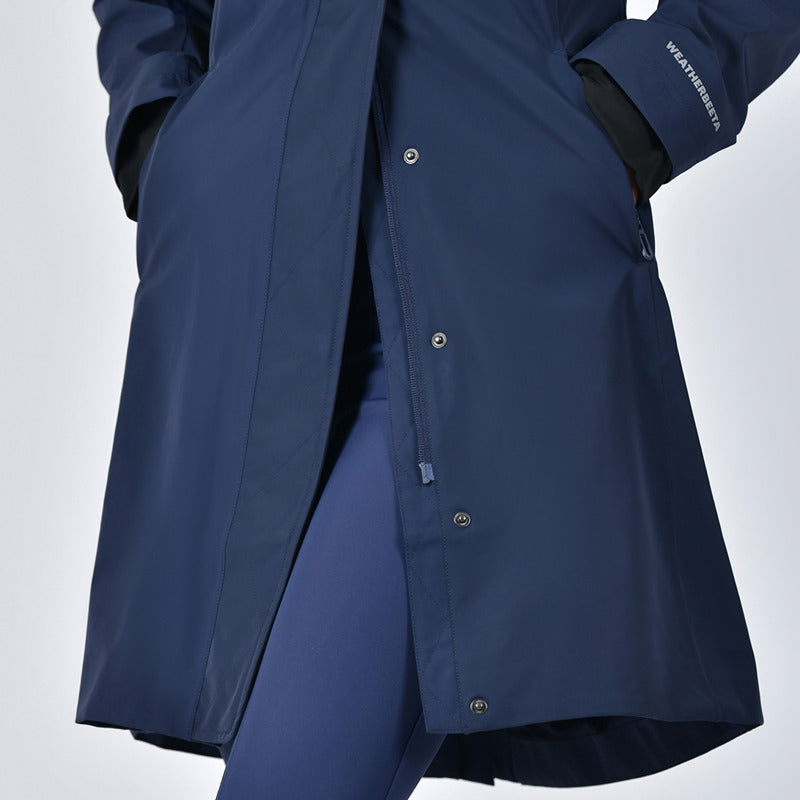 Person wearing a Weatherbeeta Protect Waterproof Longline Riding Jacket Navy, hands in pockets.