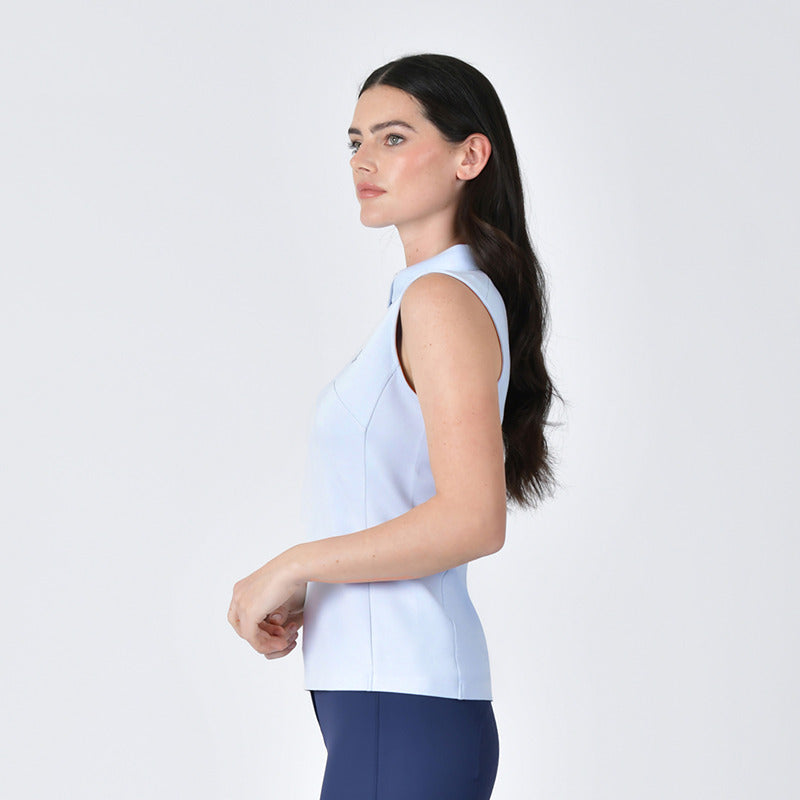 Woman wears Weatherbeeta 37.5 Sleeveless Performance Polo Mist Blue and navy pants, side view.