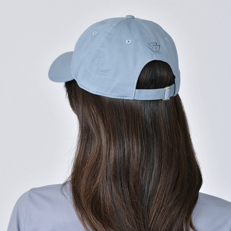 Woman wears Weatherbeeta Performance Cotton Cap in Mist Blue, looking at the camera.
