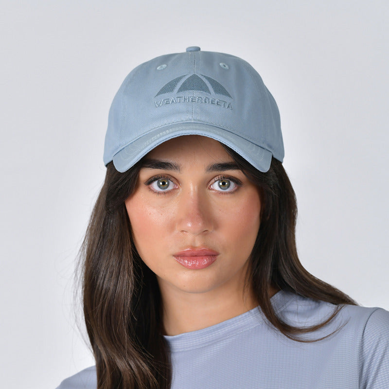 Woman wears Weatherbeeta Performance Cotton Cap in Mist Blue, looking at the camera.