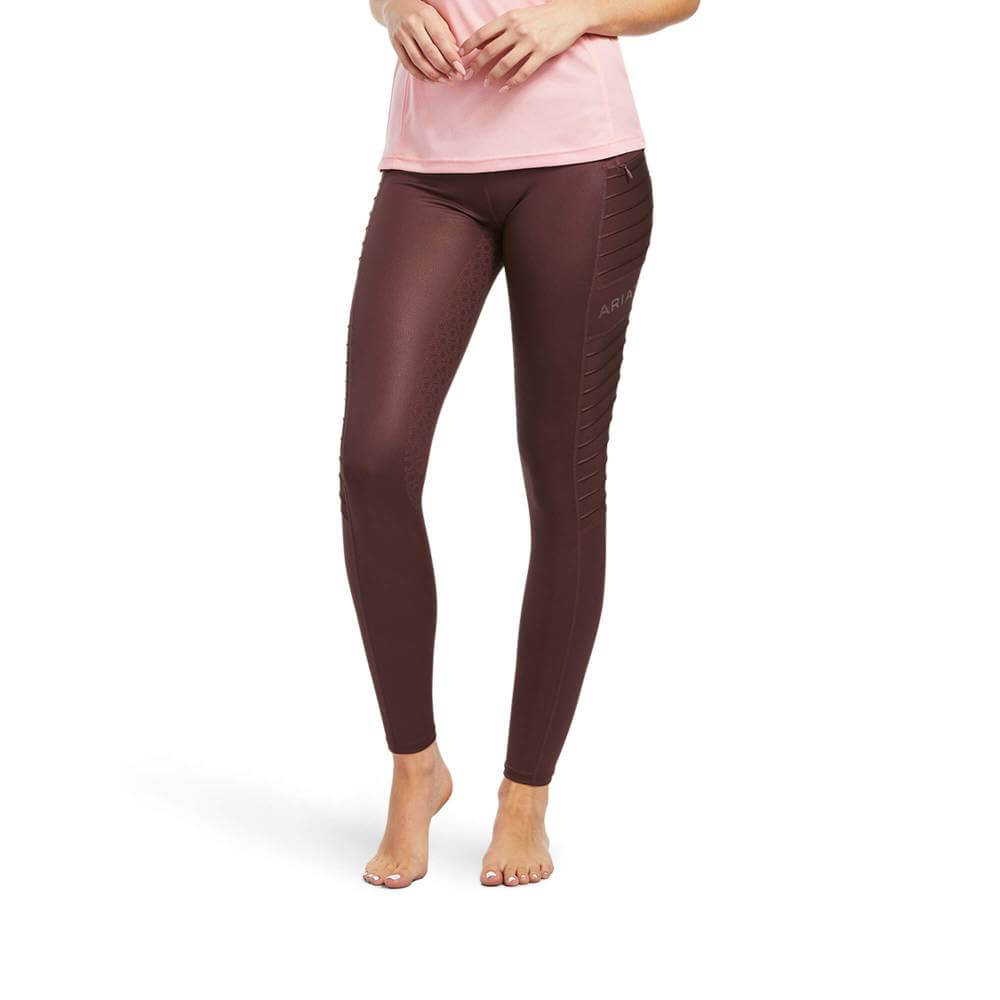 Woman in Ariat EOS Moto Full Seat Tights Deep Mahogany Hide Emboss and pink shirt, barefoot.