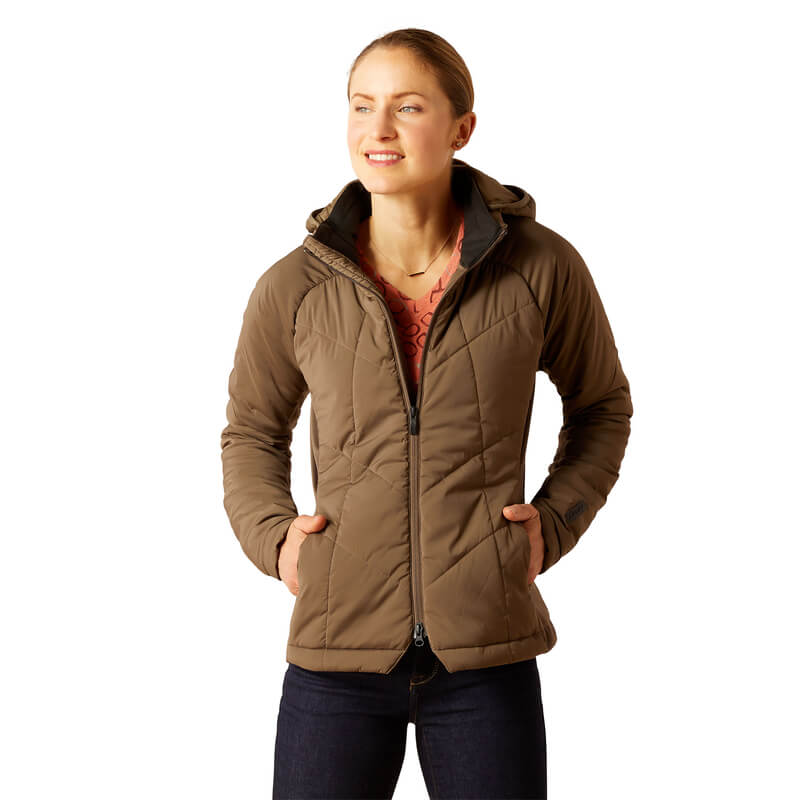 Woman smiling in Ariat Zonal Insulated Jacket Canteen and dark jeans, hands in pockets.