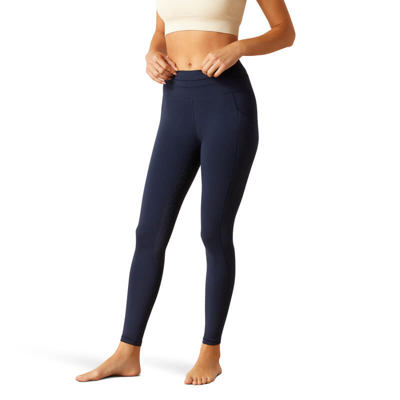 Wearing a beige crop top and Ariat Womens Eos 2.0 FS Tight Navy Eclipse, standing barefoot.