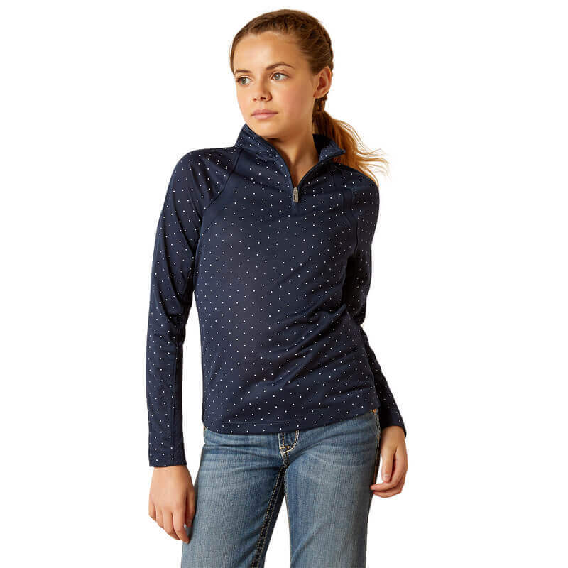Woman in Ariat Youth Sunstopper 3.0 Baselayer Navy Dot top and jeans, looking to the side.