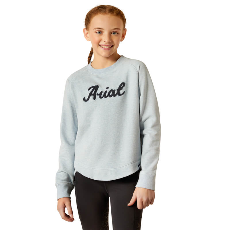 Smiling girl in Ariat Youth Benicia Sweatshirt Cerulean Heather and black pants, on white background.
