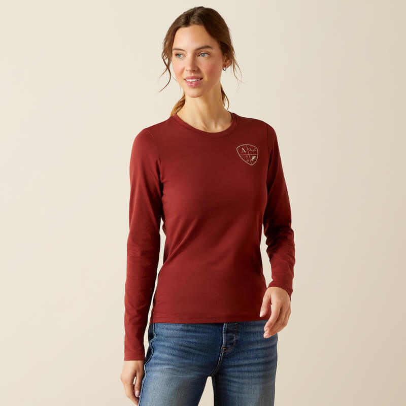 Woman in an Ariat EQ Icons Long Sleeve T-Shirt in Madder Brown stands against a plain background.