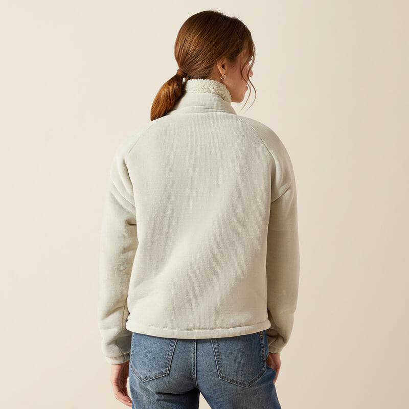 Woman in Ariat Lafayette Full Zip Fleece Pelican and blue jeans, facing away from the camera.