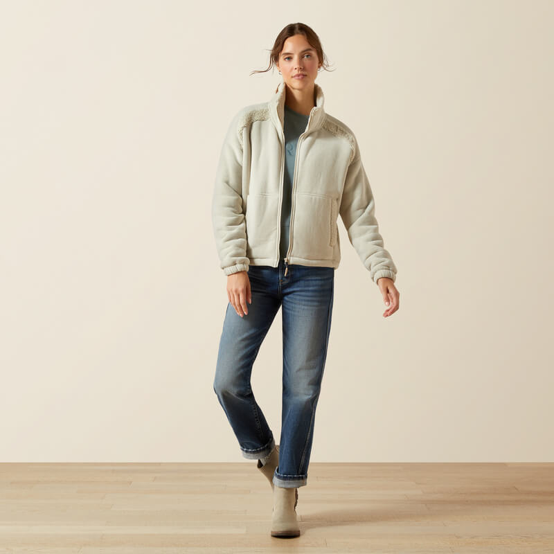 Woman in an Ariat Lafayette Full Zip Fleece stands on a wooden floor in blue jeans and boots.