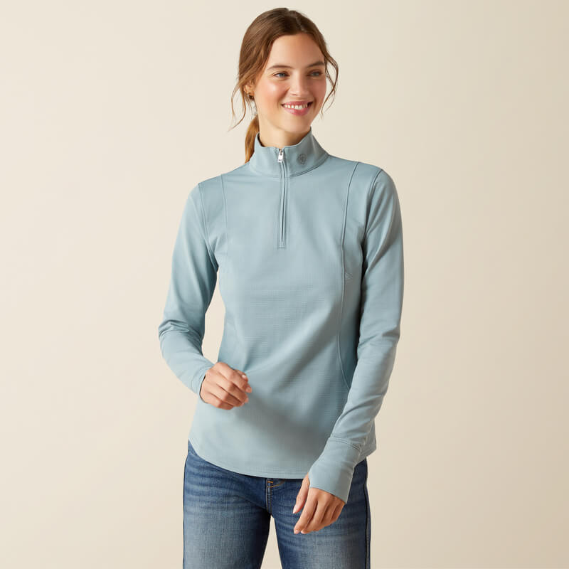 Woman in Ariat Womens Gridwork 2.0 1/4 Zip Baselayer Lead and jeans, smiling against a plain background.
