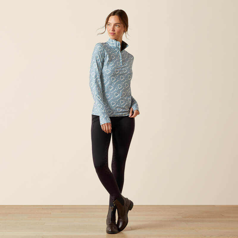 Woman in Ariat Lowell 3.0 Hardware Print baselayer, black leggings, and boots on wood floor.