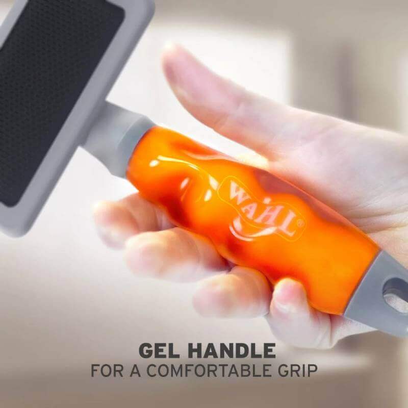 Hand holds a Wahl Large Slicker Brush Ergonomic Handle, designed for comfort and control.