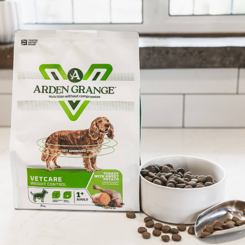 Arden Grange VetCare Weight Control dog food beside a bowl of kibble and a metal scoop.
