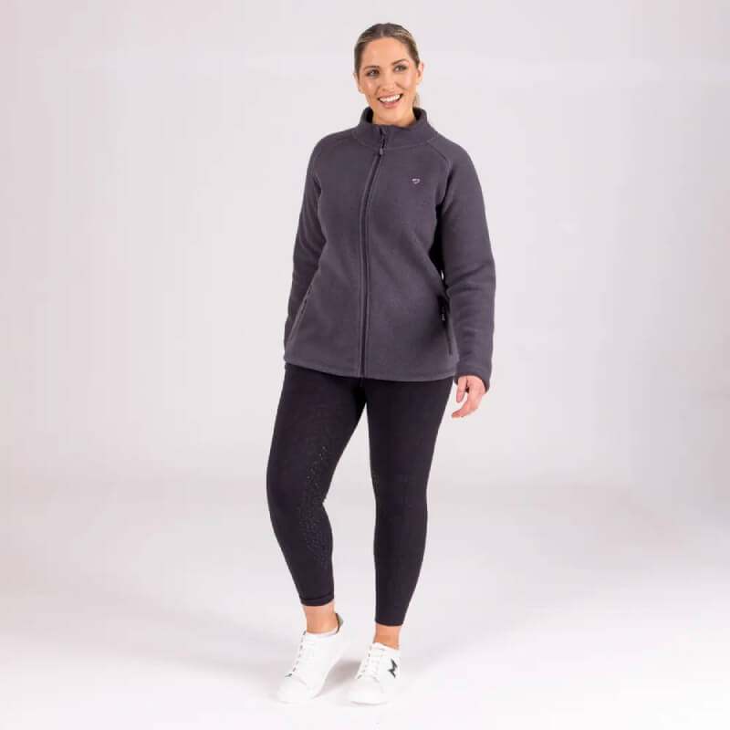 Woman smiling in Aubrion Restore Full Zip Fleece Charcoal with black leggings and thermal sneakers.