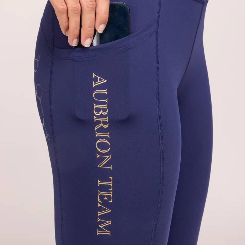 Person tucking a phone into the side pocket of Aubrion Team Riding Tights Midnight.