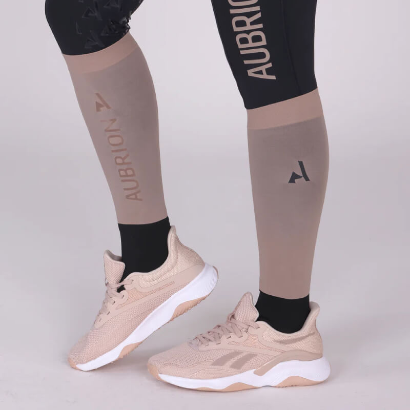 Person wearing beige Reebok sneakers and Aubrion React Performance Socks Sand with black leg sleeves.
