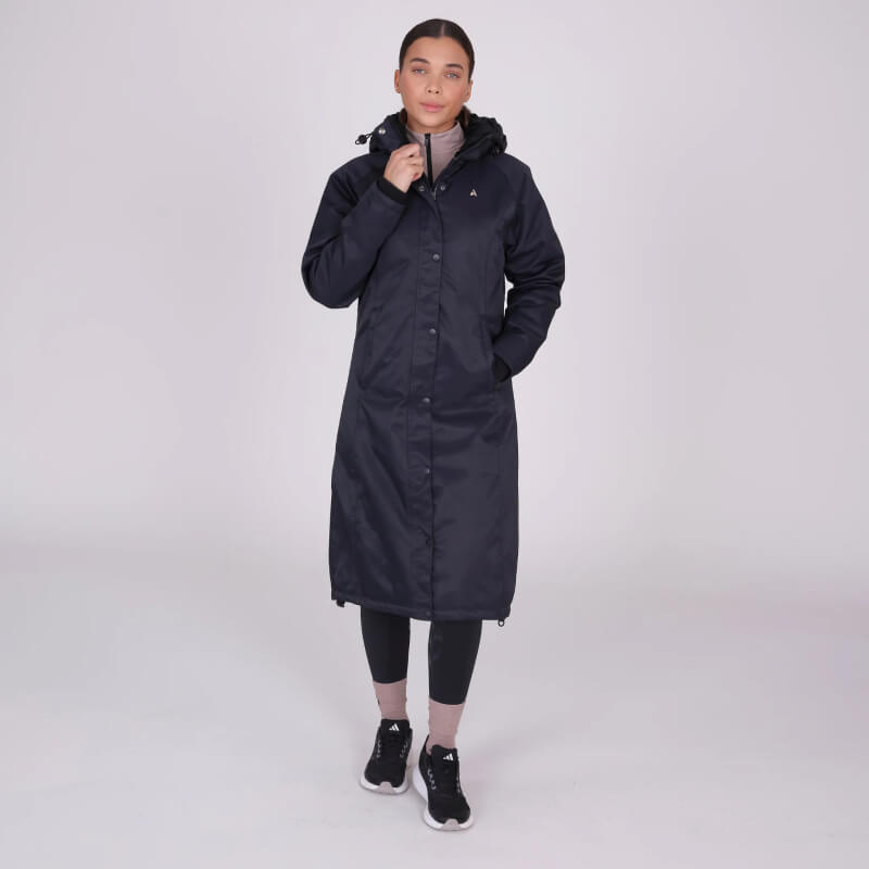 Woman wearing Shires Aubrion React Long Coat Shadow with leggings and sneakers on plain background.