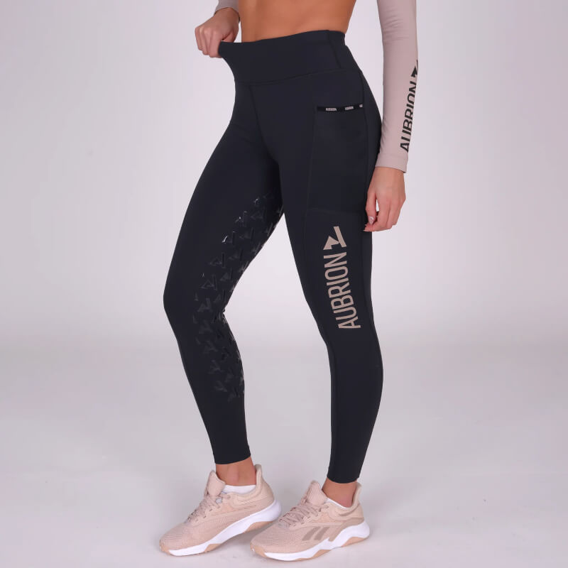 Woman wearing Aubrion Non-Stop Riding Tights Shadow, beige sneakers, and a beige crop top.