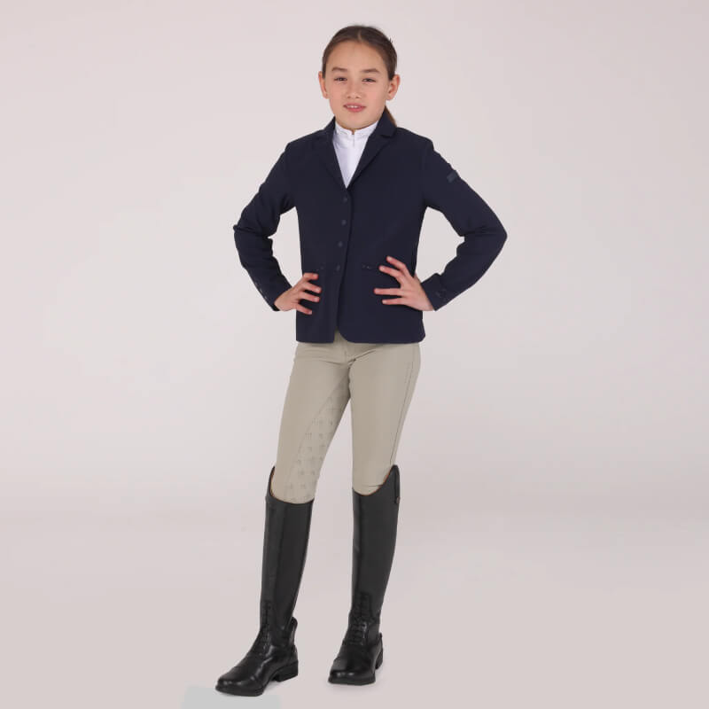 Young rider wears the Shires Aubrion Optima GX Show Jacket in Navy, hands on hips.