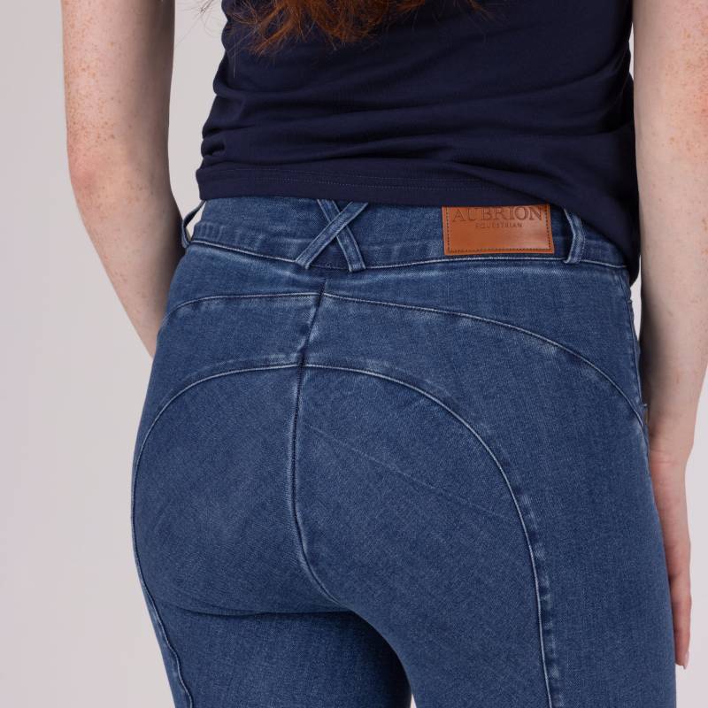 Person wears Aubrion Equestrian Jeans Denim, blue, with focus on back pocket and waistband label.