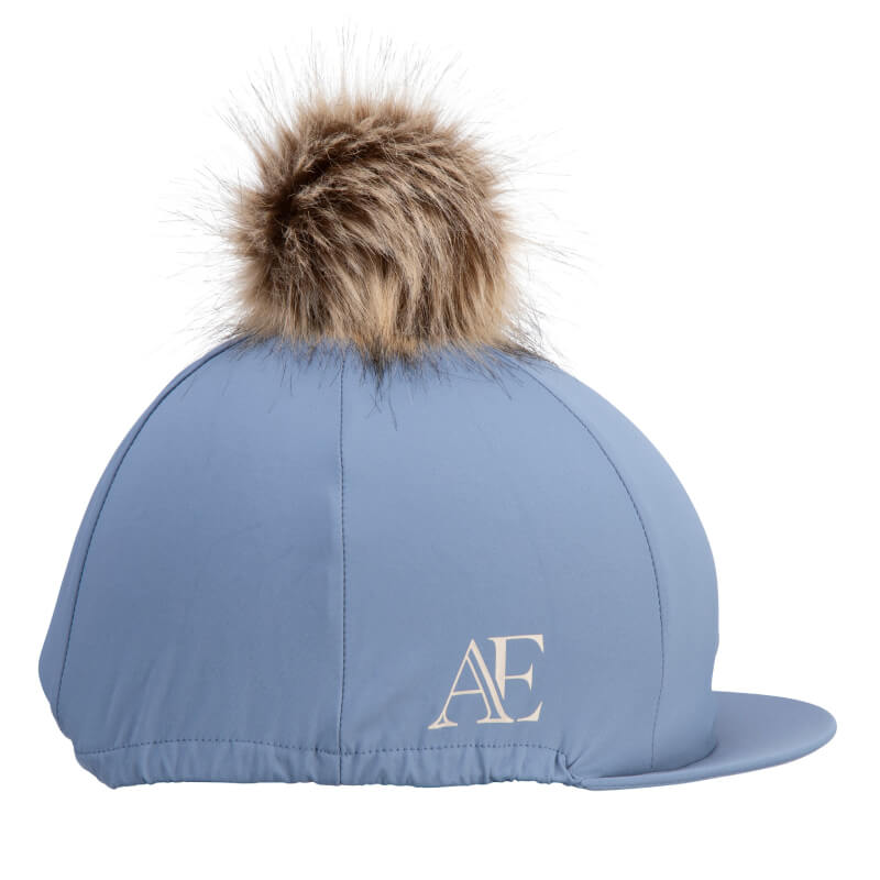 Aubrion Equestrian Hat Silk Storm: light blue cover with faux fur pom pom and Aubrion logo.