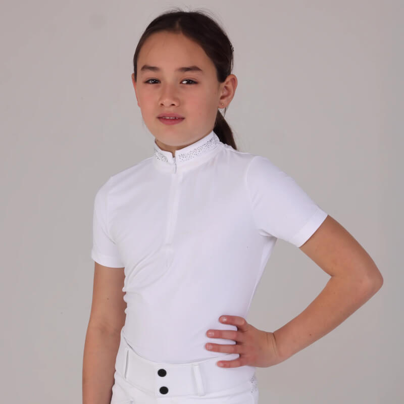 Young girl in Aubrion Optima GX Young Rider Show Shirt White, standing with hand on hip, facing forward.