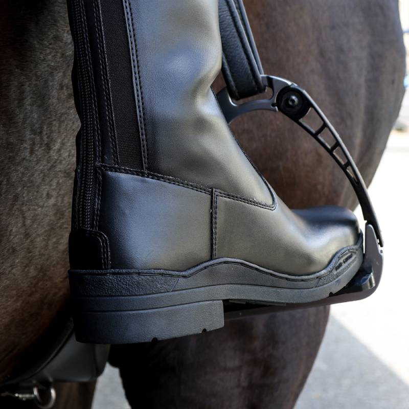 Close-up of Brogini Modena Synthetic Long Boot Wide in a stirrup on a horse.