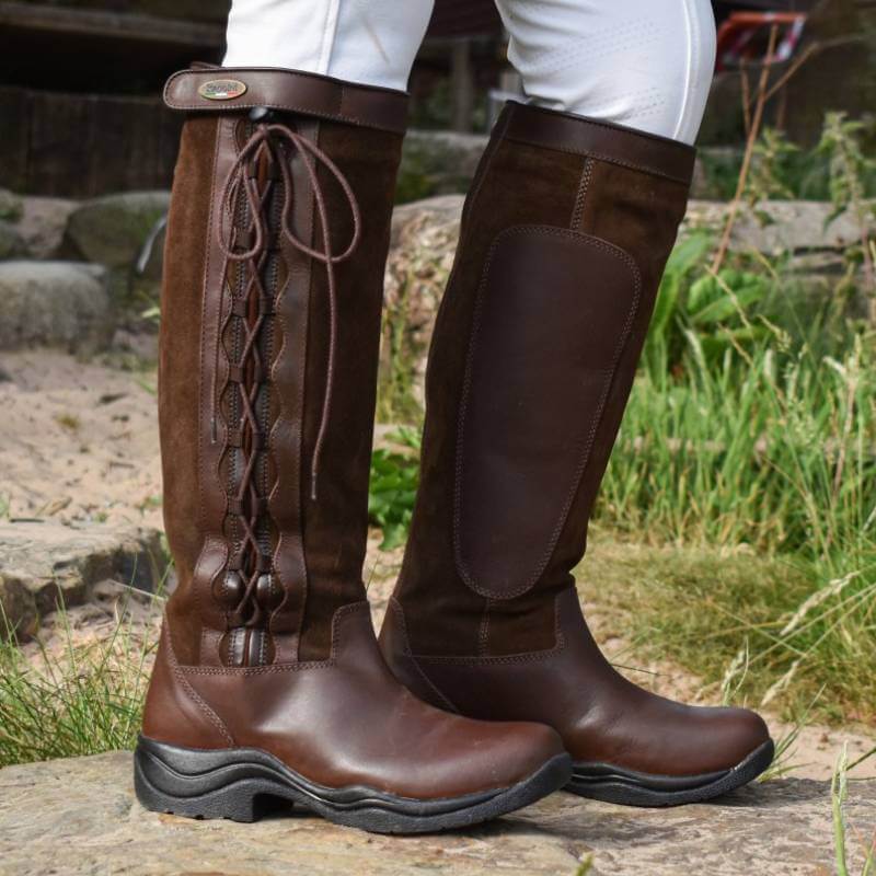 Close-up of Brogini Winchester Country Boots over white pants outdoors.