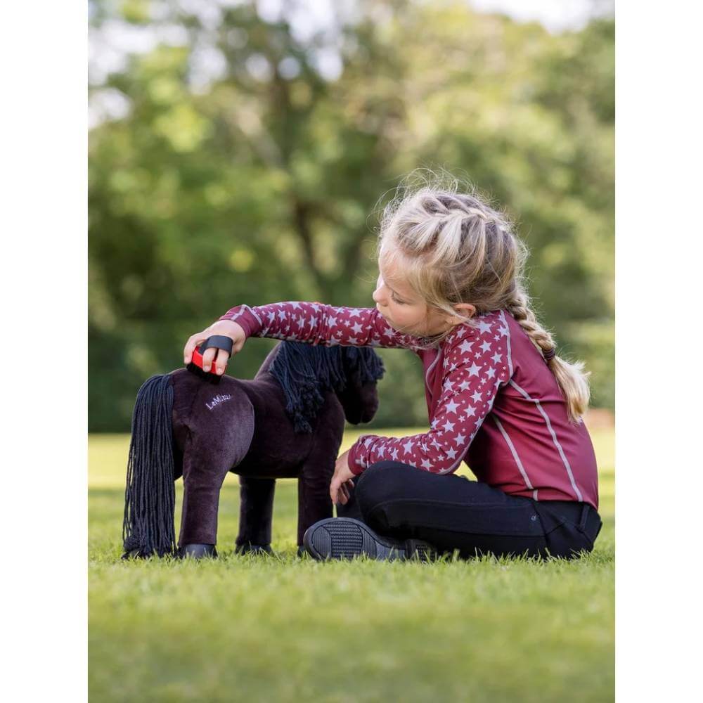 Young girl brushes her Mini LeMieux Pony with the LeMieux Mini Pony Grooming Kit outdoors.