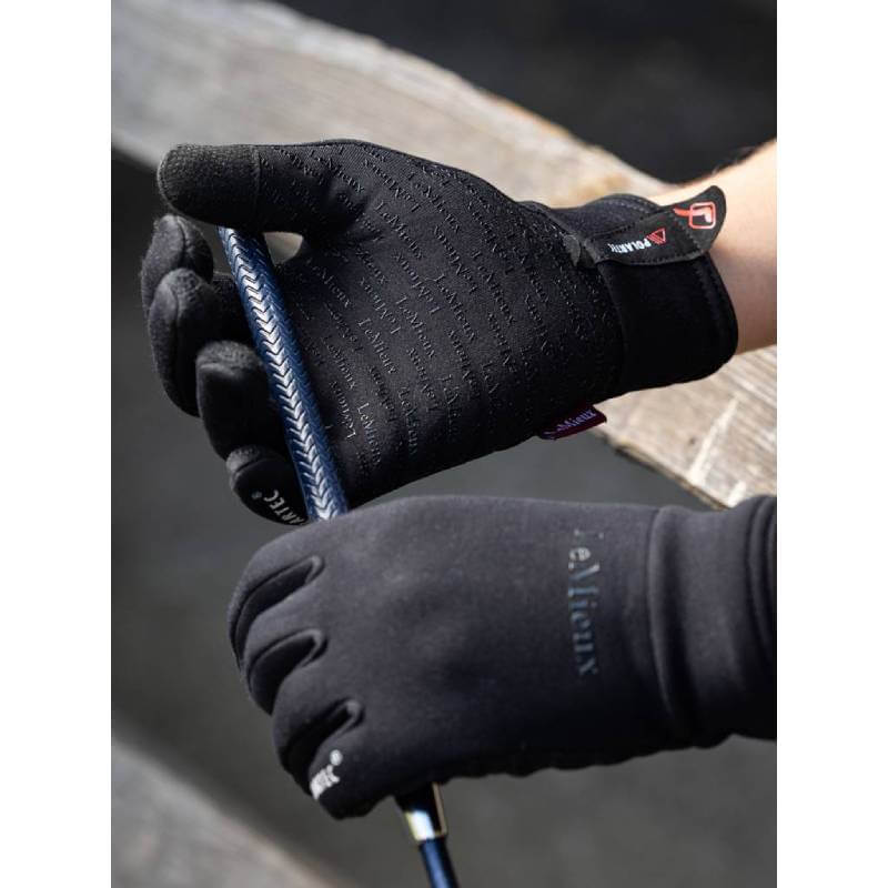 LeMieux Polartec Gloves Black 2.0 grasp a blue and white textured riding crop handle.