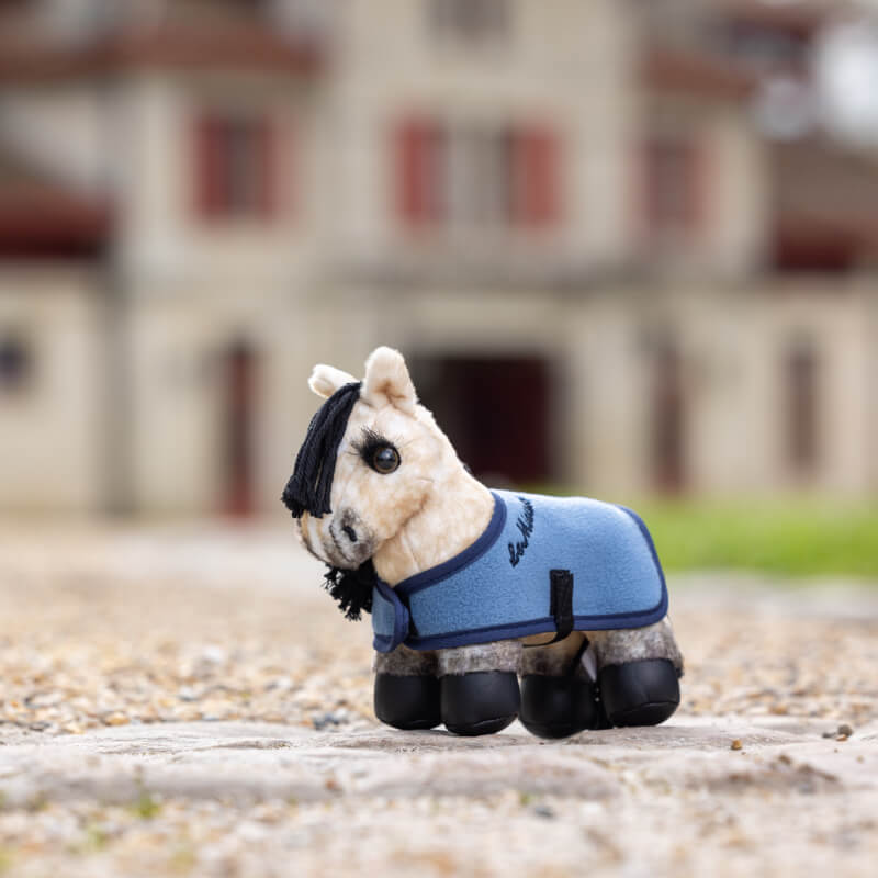 The LeMieux Tiny Pony Dream in blue stands outdoors on a cobblestone path.