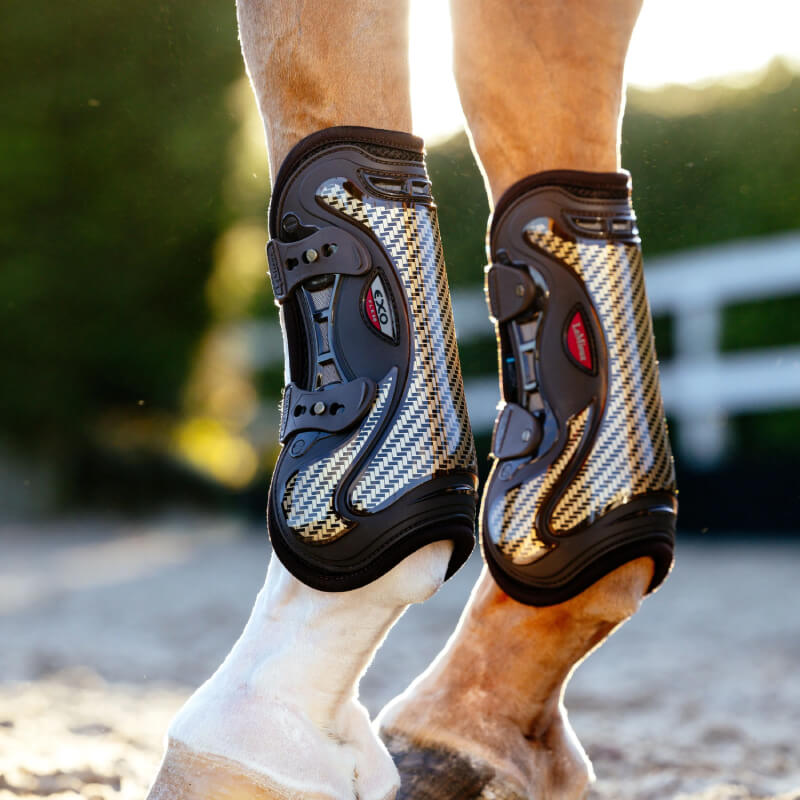 Close-up of horse's legs in LeMieux Exo-Flex Tendon Boot Brown/Gold for outdoor tendon protection.
