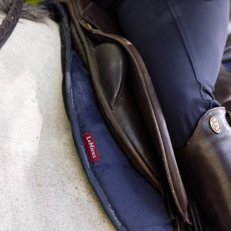 Close-up of boots on a LeMieux GP Work Pad Navy Large saddle pad for horse comfort.