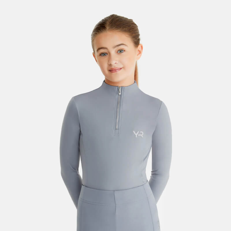 Young girl in an Aztec Diamond YR Baselayer Ash Blue, standing against a white background.