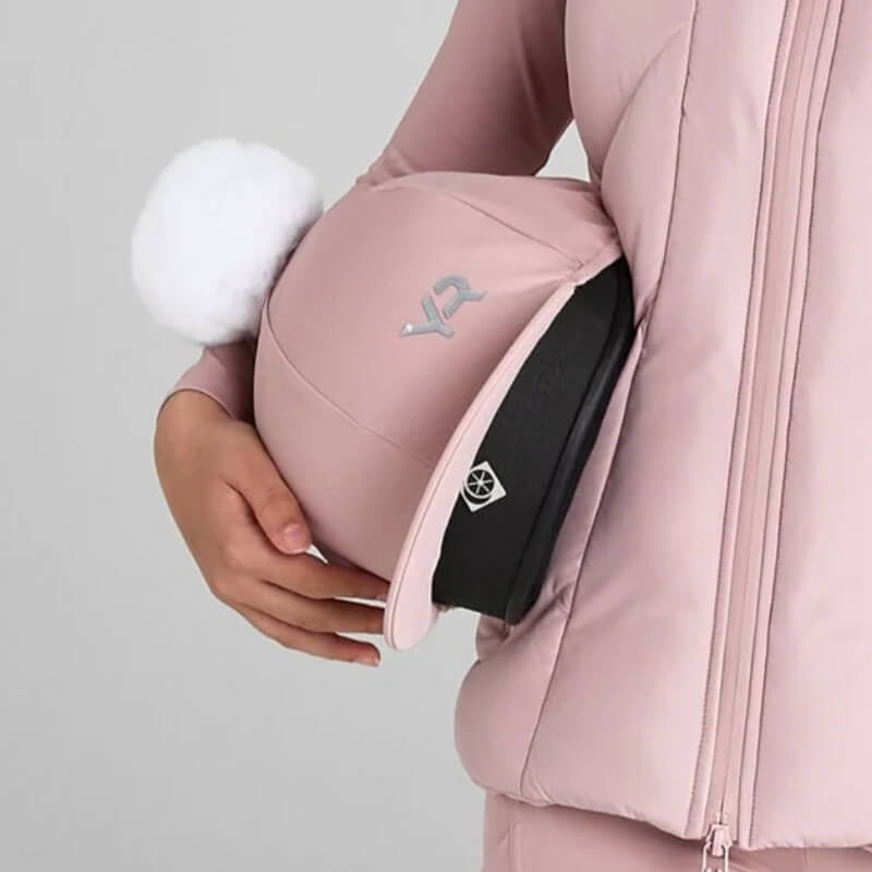 Person in pink holding Aztec Diamond YR Pom Hat Silk Pink with white pom-pom and silver logo.