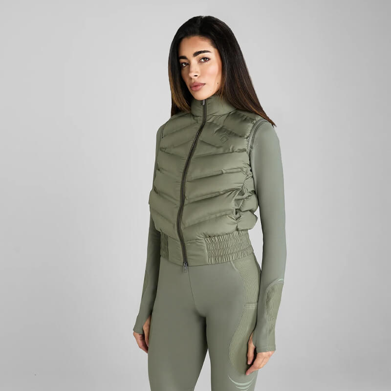 Woman in Aztec Diamond Lightweight Gilet Sage stands against a gray background.