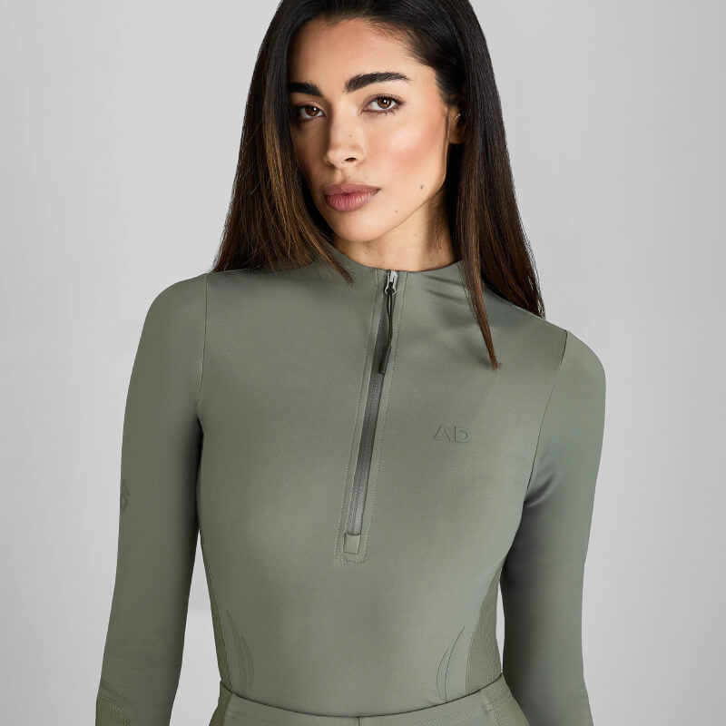 Woman in a fitted Aztec Diamond Define Baselayer Sage with UV protection on a plain background.