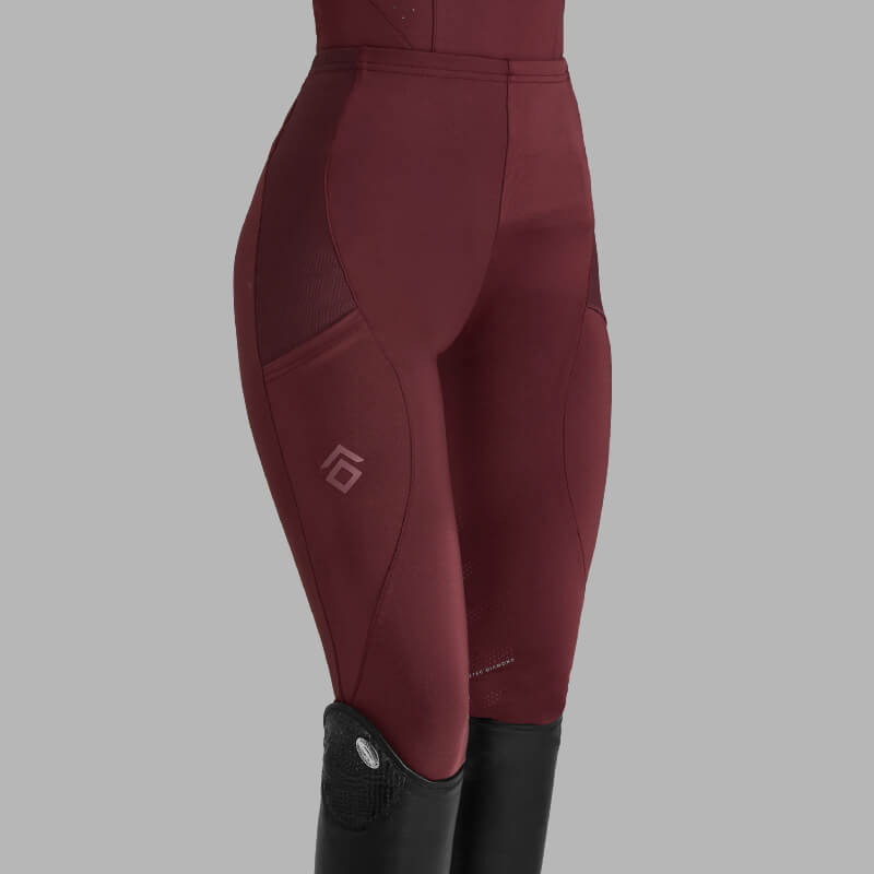 Woman wearing Aztec Diamond Core Leggings Knee Grip Cherry and black boots, gray background.