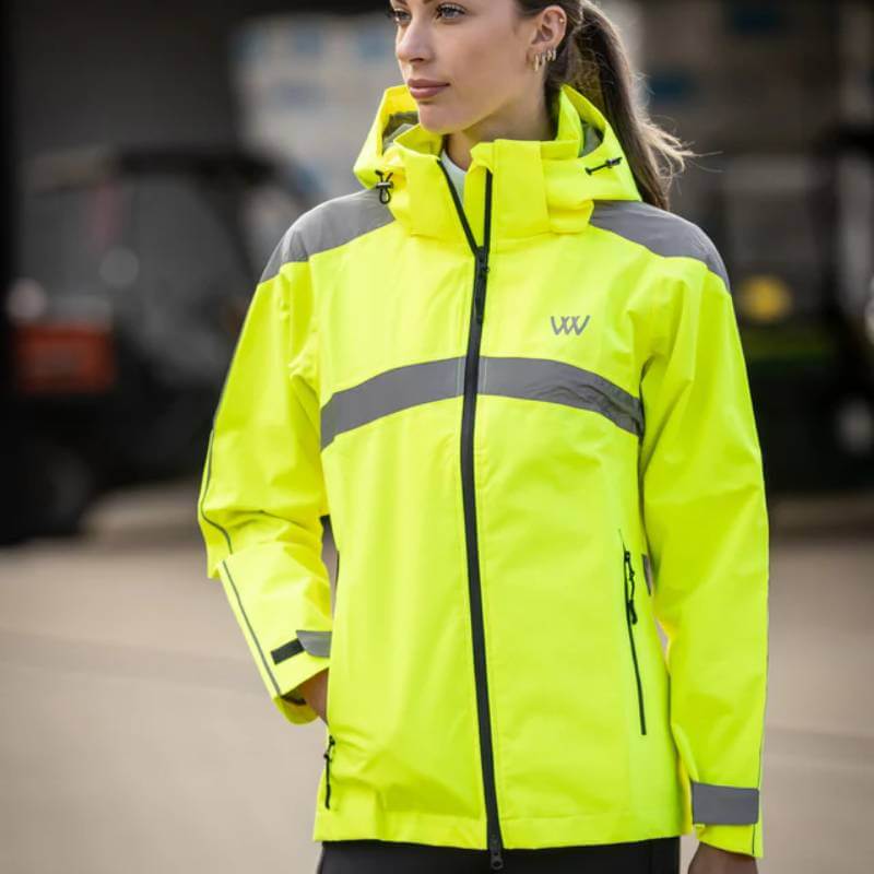 Person wearing Woof Wear All Season Waterproof Riding Jacket Hi Vis Yellow, standing outdoors.