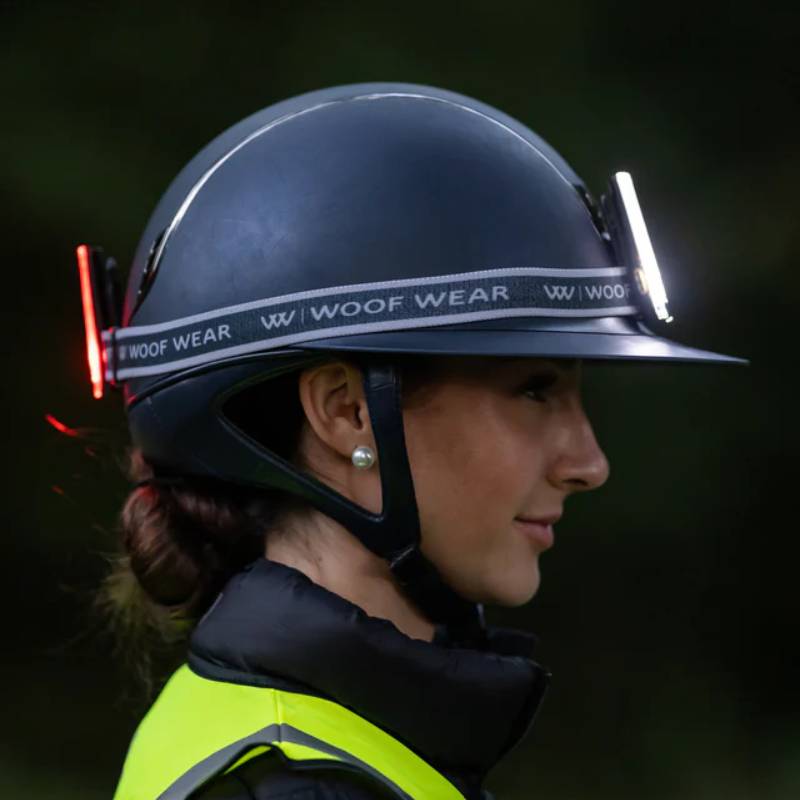 Woman in safety gear wears Woof Wear LED 3-in-1 Rider Safety Lights and a high-vis vest.