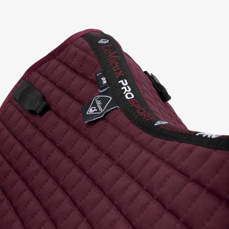 Close-up of a maroon LeMieux Prosport Dressage Sq Plain D-Ring pad with black trim.