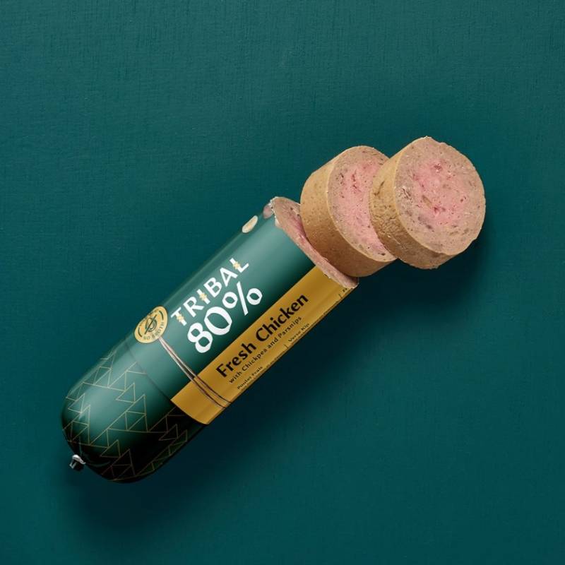 Tribal 80% Dog Sausage 300g, grain free, with fresh chicken; sliced on green background.