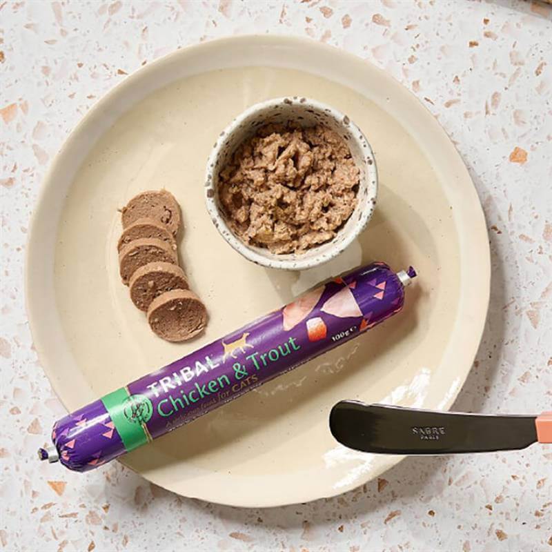 Tribal Cat Sausage 100g, sliced on a plate with wet food and a knife.