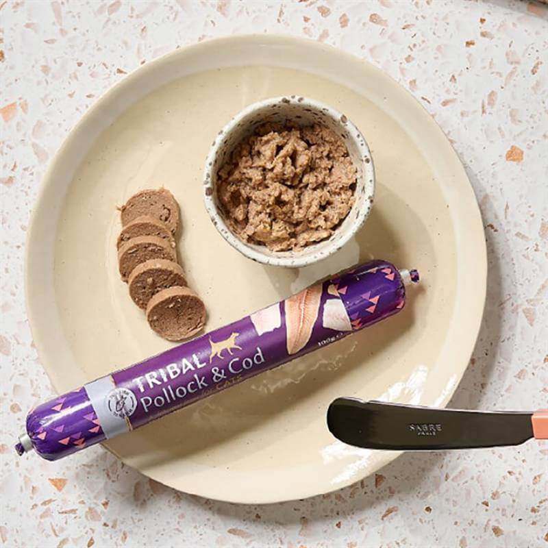 Purple-packaged Tribal Cat Sausage 100g with grain-free pollock & cod cat food in a bowl.